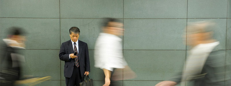 Man using phone on a busy district 