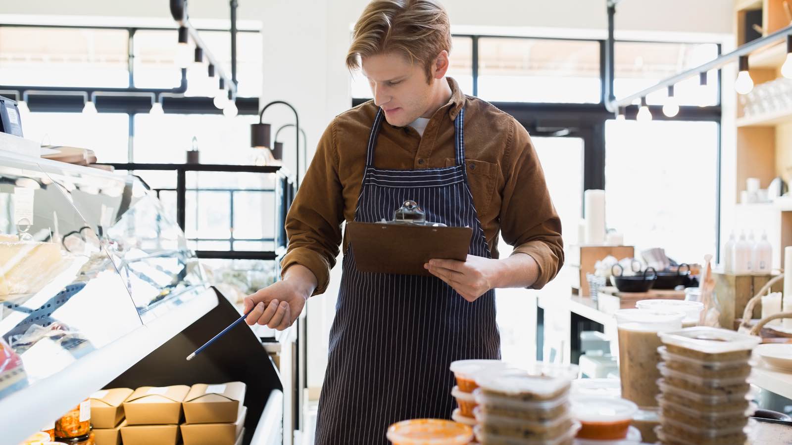 Shopkeeper holding a clipboard and checking his inventory.