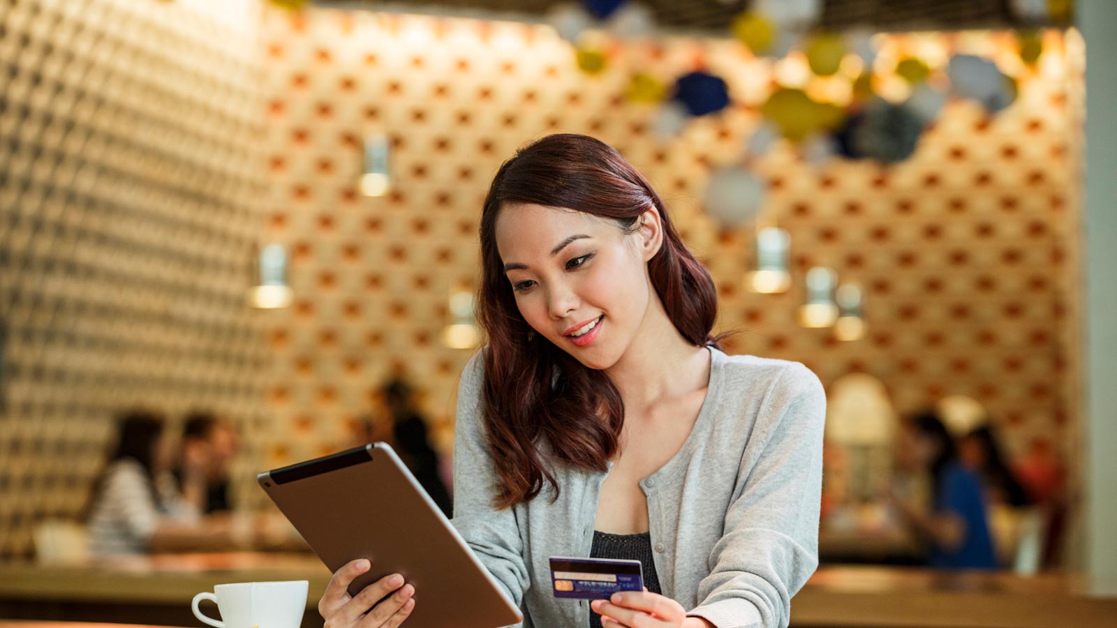 The woman uses a tablet and credit card to make sure she uses the safest way to purchase online.