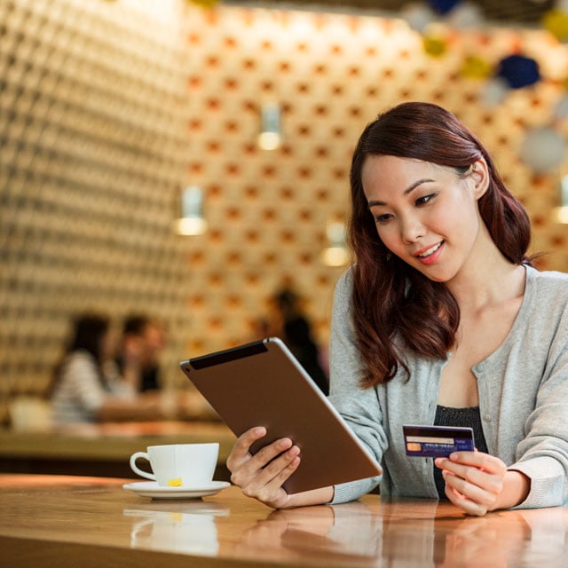 The woman uses a tablet and credit card to make sure she uses the safest way to purchase online.